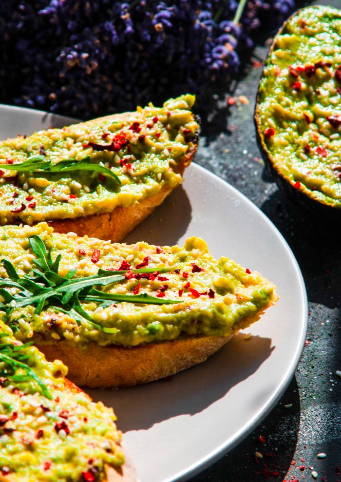 Fresh avocado toast garnished with arugula and spices, a perfect healthy breakfast option.