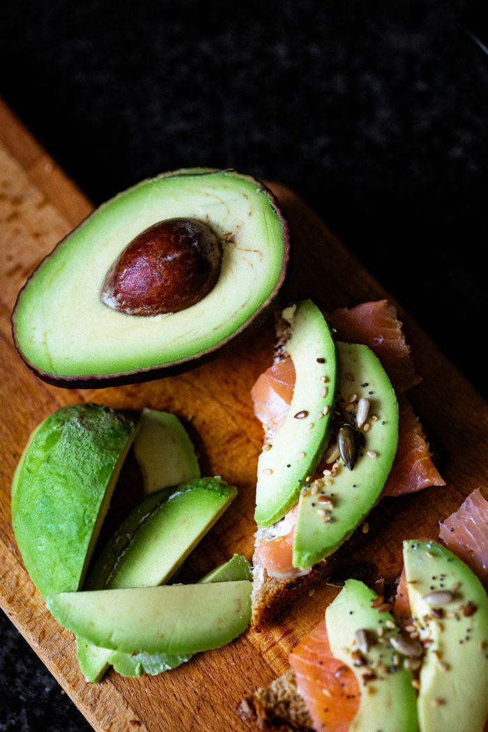 Top view of fresh avocado and smoked salmon on a wooden cutting board.