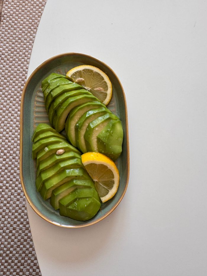 Artistic presentation of sliced avocado with lemon on a plate.