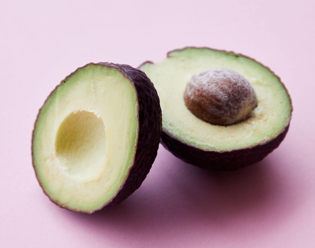 gallery-2 High angle of healthy ripe avocado with seed casting shadow on pink background